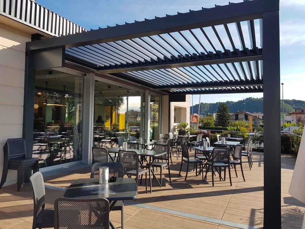 Terraza de bar con pérgola bioclimática negra con lamas orientables abiertas - Cerramiento para hostelería exterior