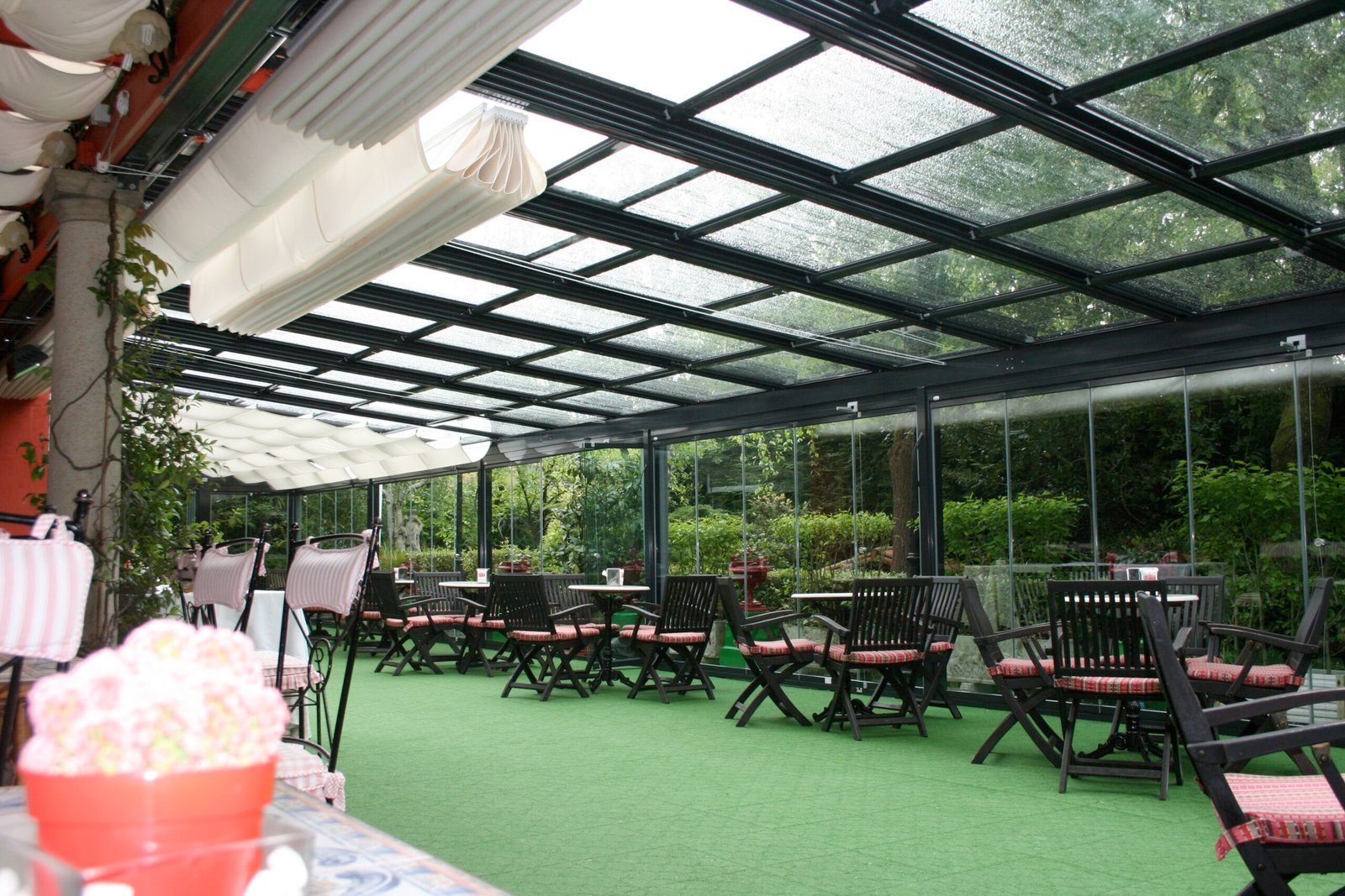 Restaurante con pérgola bioclimática negra con techo de vidrio y cortinas de cristal - Cerramiento para terraza de hostelería