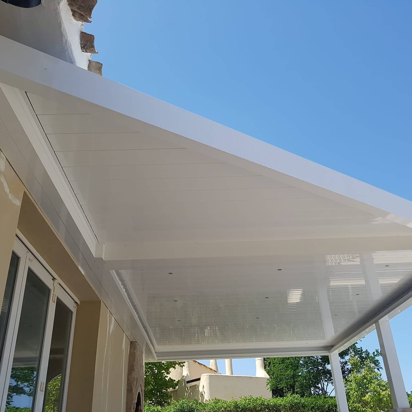 Techo de pérgola bioclimática blanca con lamas cerradas vista interior - opción techo de cristal vs pérgola